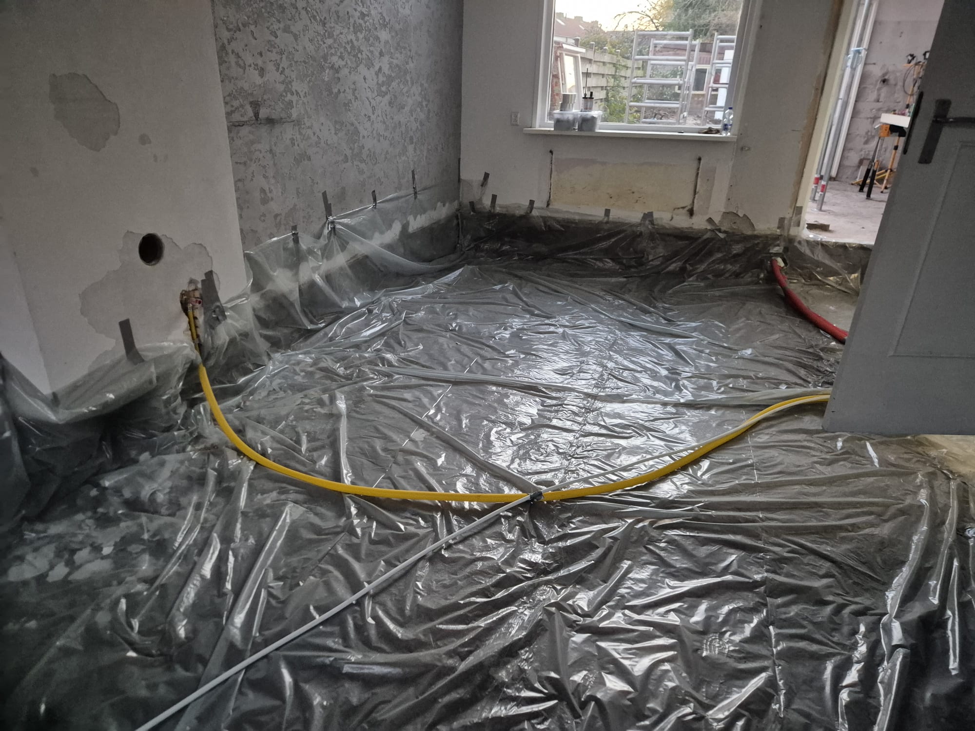 Kale ruimte in ruwbouw met de vloer afgedekt door plastic folie